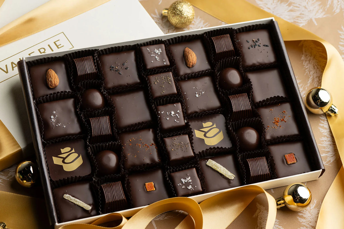 Box of assorted chocolates with a gold design on a decorative surface.