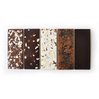 A selection of five artisan chocolate bars, each with unique toppings and flavors, arranged in a row.